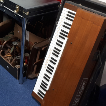 A Logan Electronic Piano String Synthesizer in a teak veneered case and housed in a black Tolex covered case for protection. Made between 1972 and 1983 in Italy, this example’s serial number 9729 identifies it as a pretty early one in lovely condition.