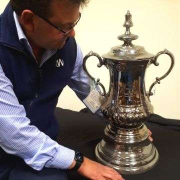 Auctioneer Richard Winterton with a Portmeirion ceramic replica of the FA Cup.