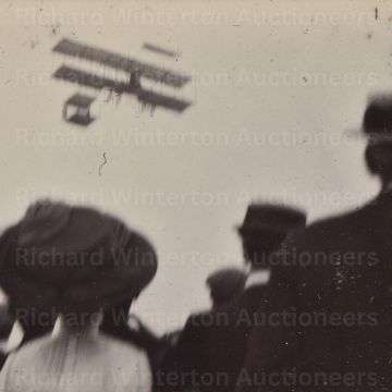 A crowd watches an early aircraft in flight at the 1910 International Aviation Meeting at Bournemouth.